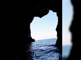 A stunning view from inside a cave looking out to the ocean, showcasing the natural beauty of coastal landmarks.