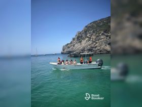 A lively group enjoys a boat tour along the stunning coastline, surrounded by clear turquoise waters and rocky cliffs — perfect for adventure seekers.
