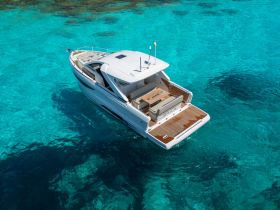 A stunning aerial view of a sleek yacht cruising through crystal-clear waters, showcasing its elegant design and inviting deck space.