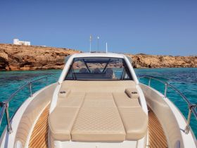 A stunning view of the front deck of a yacht, showcasing its luxurious seating and the beautiful turquoise waters in the background, perfect for a day of relaxation on the sea.
