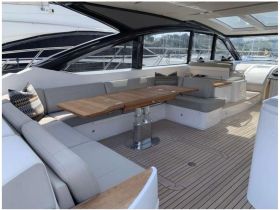 A stylish interior view of a yacht's cabin featuring comfortable seating and a dining area, perfect for relaxing and entertaining on the water.