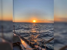 A serene sunset view from the deck of a sailboat, showcasing the tranquil waters and golden hues of the evening sky — perfect for romantic sailing experiences.