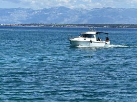 A sleek speedboat navigates through clear waters, showcasing a beautiful backdrop of mountains — perfect for a day of adventure on the water.
