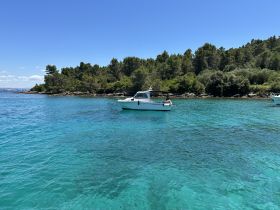 A scenic view of a boat navigating through crystal-clear waters, surrounded by lush greenery — perfect for exploring coastal destinations.