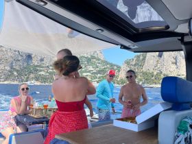 A joyful family gathering on a boat, enjoying drinks and celebrating together against a stunning coastal backdrop — perfect for memorable summer outings.