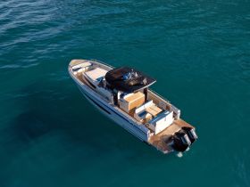 Aerial view of a sleek boat cruising through clear turquoise waters, showcasing its elegant design and spacious deck — perfect for luxury outings on the water.