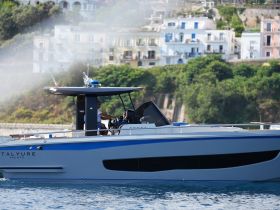 A sleek yacht is captured underway, showcasing its modern design and elegance against a picturesque coastal backdrop.