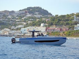 A sleek yacht cruising through clear waters, showcasing its elegant design against a picturesque coastal backdrop.