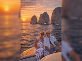 A couple enjoys a romantic sunset on a yacht, capturing a perfect moment against the stunning backdrop of rock formations and golden skies.