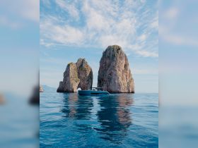 A sleek boat navigates the serene waters near iconic rock formations, showcasing the beauty of the coastline and perfect for scenic tours.