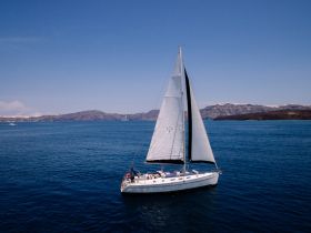 A stunning aerial view of a sailboat gracefully navigating the serene waters, showcasing the beauty of sailing in picturesque surroundings.