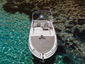 A stunning aerial view of a sleek speedboat anchored in crystal-clear waters, showcasing the perfect setting for a day of relaxation and adventure on the water.