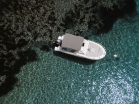 Aerial view of a sleek boat anchored in crystal-clear waters, showcasing the beauty of the marine environment.