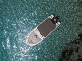 A stunning aerial view of a sleek boat gliding over crystal-clear waters, showcasing the beauty of a perfect day on the water.