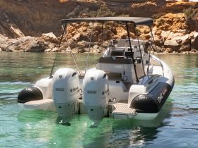 A sleek speedboat is docked in crystal-clear waters, showcasing its powerful twin Yamaha engines — perfect for thrilling water adventures.