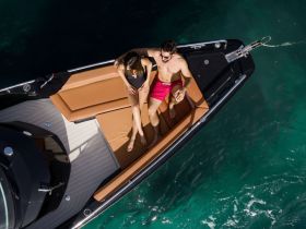 A couple enjoys a relaxing moment on the deck of a sleek boat, perfect for sunbathing and enjoying the water.