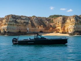 A sleek speedboat navigates the clear waters near stunning cliffs, showcasing the perfect vessel for coastal adventures.