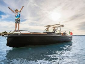 A joyful child stands triumphantly on the bow of a boat, capturing the essence of fun and adventure on the water.