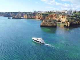 A stunning aerial view of a yacht cruising through crystal-clear waters, surrounded by dramatic cliffs and coastal scenery, perfect for showcasing luxury boating experiences.