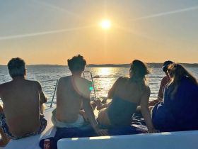 A group enjoys a stunning sunset view from the deck of a yacht, creating a perfect atmosphere for relaxation and celebration on the water.