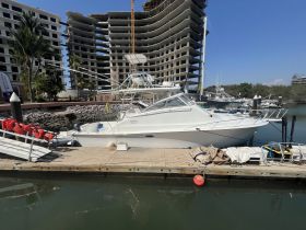 A sleek yacht docked at a marina, showcasing its elegant design against a backdrop of modern buildings — perfect for luxury boating experiences.