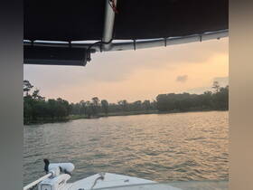 A serene view from the bow of a boat, showcasing the calm waters and lush greenery at sunset, perfect for peaceful outings on the water.
