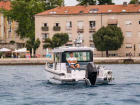 A man relaxes on a boat while cruising near the shore, showcasing a perfect day on the water with scenic views.