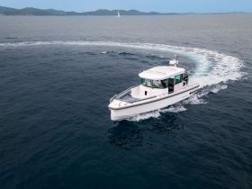 A sleek speedboat glides through the open water, showcasing its design and performance in a stunning aerial view.