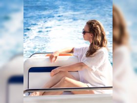A woman relaxes on the deck of a boat, enjoying the ocean breeze and sunshine — a perfect moment for unwinding on the water.