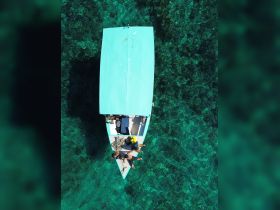 Aerial view of a vibrant boat with guests enjoying the clear turquoise waters, perfect for a day of adventure and relaxation on the water.
