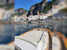 A stunning view from the deck of a yacht, showcasing the picturesque coastal town and rocky cliffs in the background — perfect for exploring the Amalfi Coast.