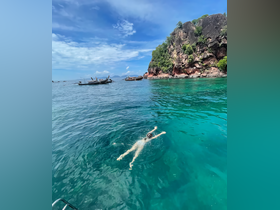 A swimmer enjoys the crystal-clear waters near a rocky island, showcasing the beauty of tropical adventures and perfect for snorkeling or swimming excursions.