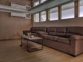 A cozy lounge area inside a boat featuring comfortable seating and a coffee table, perfect for relaxing during a cruise.