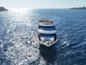 A stunning view of a yacht cruising through sparkling blue waters, showcasing its elegant design and perfect for luxury charters.