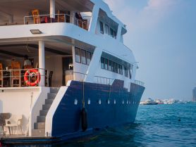 A side view of a luxurious yacht docked in calm waters, showcasing its spacious upper deck and inviting dining area — perfect for private charters and events.
