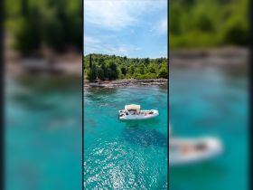 Aerial view of a sleek speedboat anchored in crystal-clear turquoise waters, surrounded by lush greenery — perfect for exploring coastal destinations.