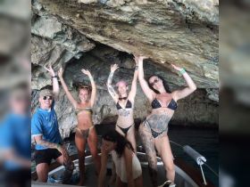 A lively group of friends celebrates inside a cave while enjoying their boat trip, showcasing the fun and adventure of exploring hidden gems on the water.