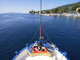 A couple relaxes on the bow of a yacht, enjoying the serene waters and picturesque scenery — a perfect moment for leisure on the water.
