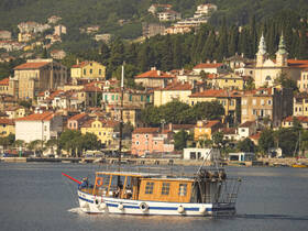 A charming boat navigates through a picturesque harbor, surrounded by colorful coastal buildings and lush greenery, showcasing the beauty of waterfront destinations.