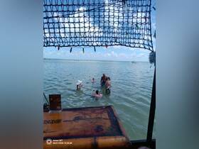 A lively group enjoys a sandbar stop, swimming and socializing in shallow waters — a perfect setting for fun and relaxation on the water.