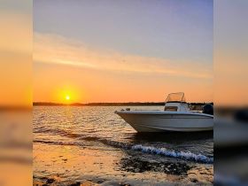 A serene sunset view featuring a speedboat anchored in calm waters, perfect for capturing the beauty of evening boat outings.