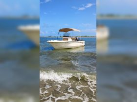 A sleek speedboat anchored in shallow waters, showcasing its design against a clear blue sky — perfect for day trips and water adventures.