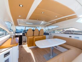 A spacious and elegantly designed interior of a yacht, featuring comfortable seating and a well-equipped helm, perfect for relaxing and navigating the waters.