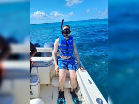 A snorkeler prepares for an underwater adventure while seated on a boat, surrounded by stunning blue waters — perfect for exploring marine life.