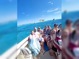 A lively group enjoys a day on the water, soaking up the sun aboard a boat with a picturesque island backdrop — perfect for memorable outings and celebrations.