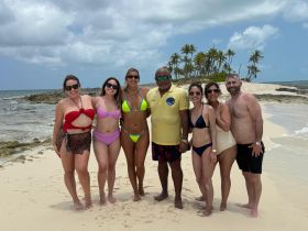 A joyful group poses on the beach, showcasing their vibrant swimwear against a picturesque tropical backdrop — perfect for beach outings and celebrations.