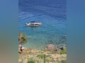 A lively scene with a group enjoying a day on the water, swimming around a boat in crystal-clear waters — perfect for summer adventures and beach fun.