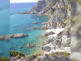 A stunning view of a secluded beach surrounded by rocky cliffs and crystal-clear turquoise waters, perfect for exploring hidden gems along the coastline.