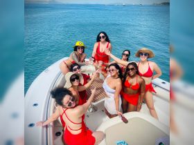 A lively group of friends celebrates on a boat, raising cocktails in a toast — perfect for bachelorette parties or summer gatherings on the water.