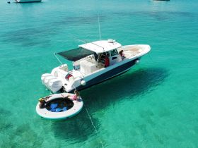 A fun day on the water with friends enjoying a floating mat next to a boat in crystal-clear waters — perfect for summer adventures and relaxation.